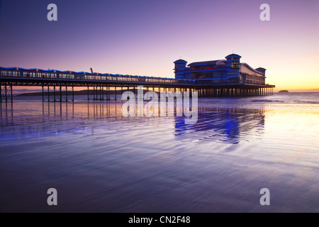 Dämmerung über dem Grand Pier bei Weston-Super-Mare, Somerset, England, UK spiegelt sich in dem nassen Sand des Strandes bei Flut. Stockfoto