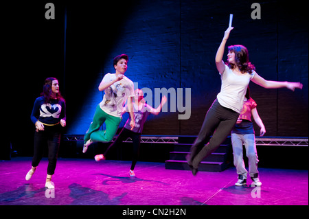 Eine Gruppe von jungen und Mädchen, Teenager singen und tanzen in einem Amateur Musiktheater-Leistung-Produktion in einem Theater. UK Stockfoto