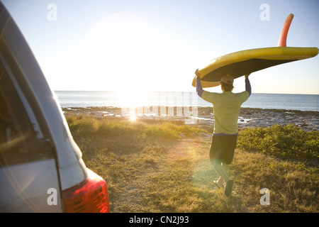 Mann trägt Paddleboard am Strand, Florida Keys, USA Stockfoto