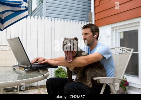 Mann mit Laptop mit Hund auf Schoß Stockfoto