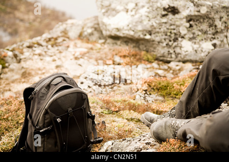 Man ruht auf Felsen mit Rucksack Stockfoto