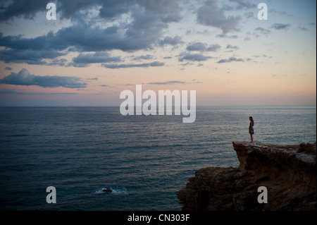 Frau stehend auf Klippe Blick auf das Meer bei Sonnenuntergang Stockfoto