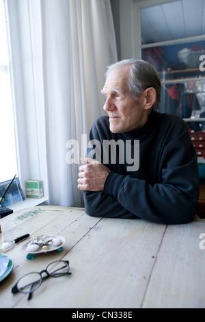 Senior woman Blick aus Fenster Stockfoto