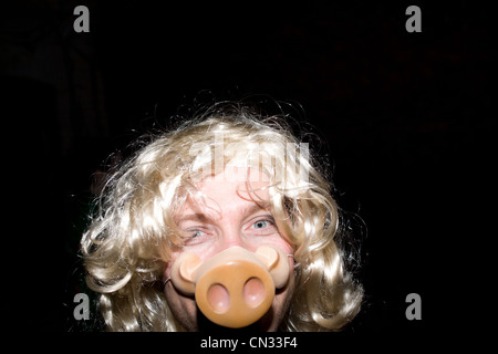 Mann mit blonder Perücke und des Schweines Schnauze Maske Stockfoto