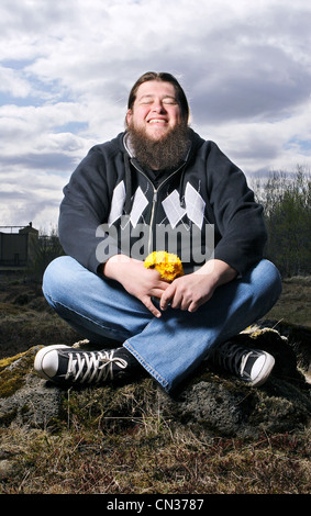 Happy bärtigen Mann sitzt im Feld mit Blumen Stockfoto