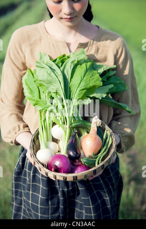 Junge Frau im Feld Betrieb Korb mit einheimische Gemüse Stockfoto