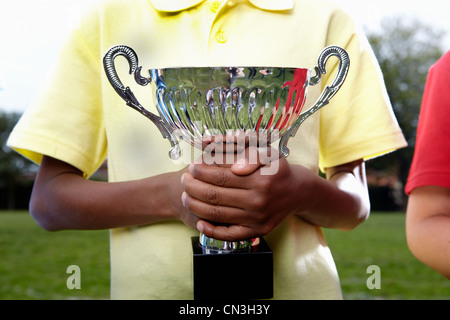 Boy holding Trophy Cup am Spielfeld Schule Stockfoto