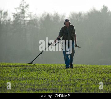 Ein Mann sucht in einem grünen Feld mit einem Metalldetektor in Dorset. Stockfoto