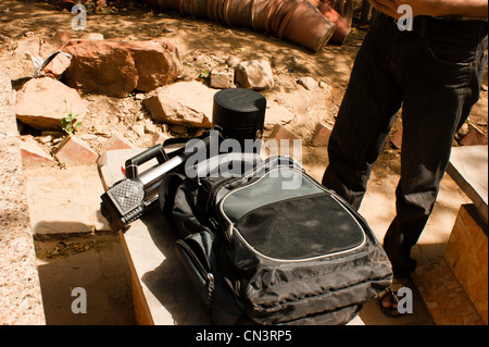 Fotograf mit seiner Ausrüstung auf eine Steinbank im Jardin des Cinq Sens in Mehrauli in Süd-Delhi. Stockfoto