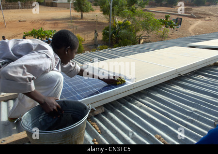 Kleiner Junge reinigt Staub von Sonnenkollektoren in Afrika Stockfoto