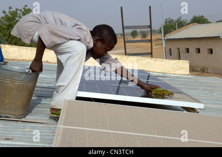 Kleiner Junge reinigt Staub von Sonnenkollektoren in Afrika Stockfoto