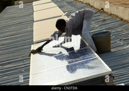 Kleiner Junge reinigt Staub von Sonnenkollektoren in Afrika Stockfoto