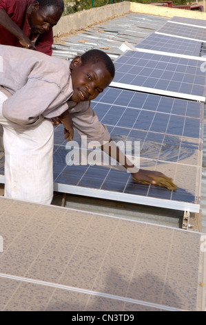 Kleiner Junge reinigt Staub von Sonnenkollektoren in Afrika Stockfoto