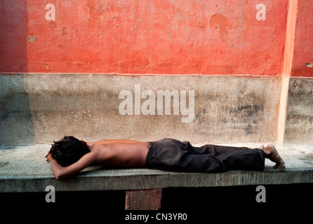 Ein Junge legt sich auf eine Bank in Indien Stockfoto