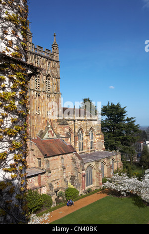 Älteres Paar, das im April auf der Bank vor dem Priorat von Great Malvern in Great Malvern, Worcestershire, Großbritannien, Zeitungen liest Stockfoto