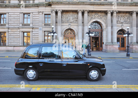 Hackney Taxi führt vorbei an der Vorderseite des Glasgow City Chambers in George Square, UK Stockfoto