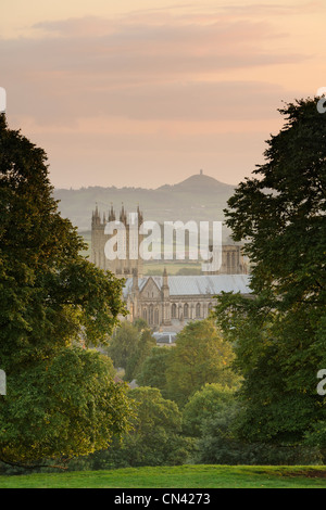 Ein paar Bäume umrahmen Wells Cathedral mit Glastonbury Tor, die in der Ferne sichtbar. Stockfoto