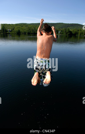 Young Boy springen weg von einem Dock, Lac des Neiges, Quebec Stockfoto