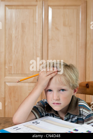 Jungen suchen verwirrt über Hausaufgaben, Porträt Stockfoto