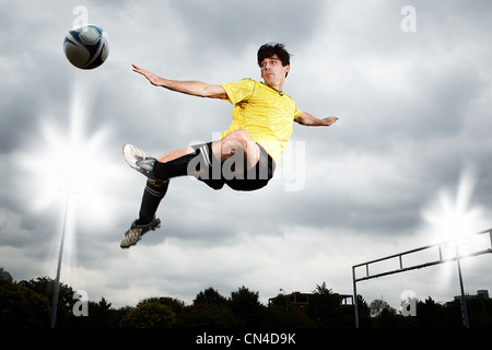 Fußball-Spieler springen um den Ball zu kicken Stockfoto