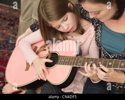 Mitte Erwachsene Frau, Tochter, akustische Gitarre zu spielen Stockfoto