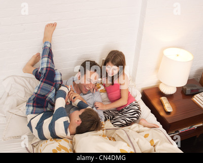 Mitte erwachsener Mann im Bett von Sohn und Tochter gekitzelt Stockfoto