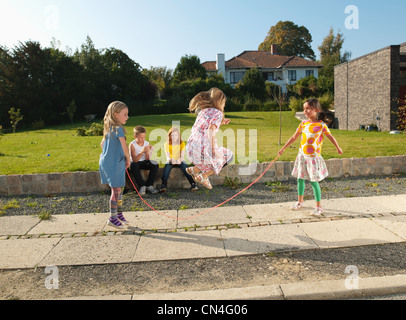 Mädchen auf Bürgersteig überspringen Stockfoto