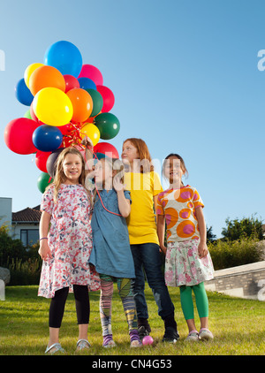 Mädchen stehen auf Rasen mit bunten Ballons Stockfoto