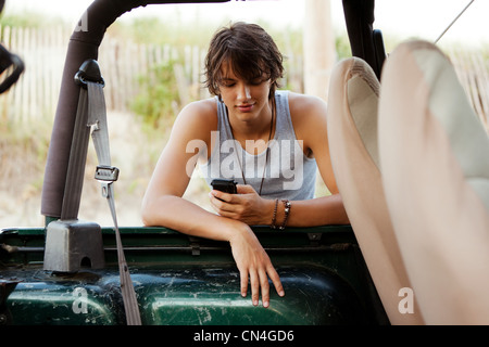 Teenager gelehnt Jeep überprüft Telefon Stockfoto