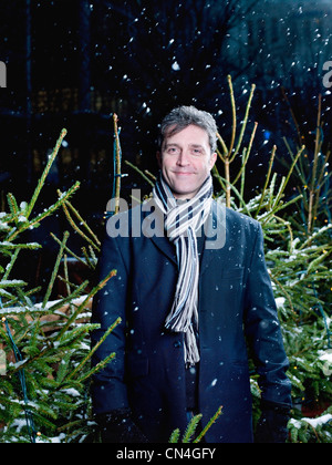 Mann stand vor Weihnachtsbäume im Schnee Stockfoto