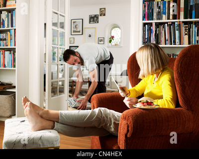 Reifer Mann als Frau sitzt im Sessel aufräumen Stockfoto