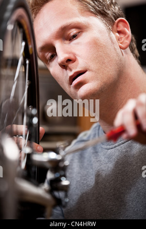 Mitte erwachsenen Mannes Reparatur Fahrrad zu Hause Stockfoto