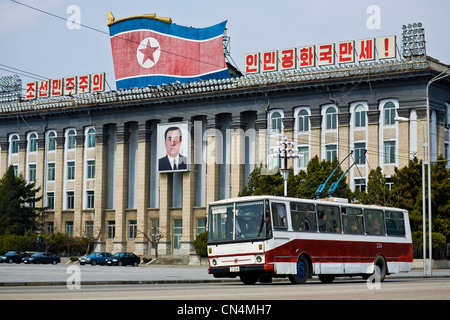 Nordkorea, Pjöngjang, Kim Il-Sung-Platz, Trolley-Bus vorbeifahren ein Porträt von Kim Il-Sung hing an der Fassade der Stockfoto