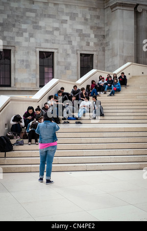 SchülerInnen Faulenzen auf der Haupttreppe des Bereichs Atrium des British Museum in London, England. Stockfoto