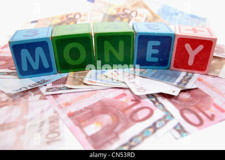 verschiedene Kinder Spielzeug Bausteine Brief vor einem weißen Hintergrund auf Geld, das Geld zu buchstabieren Stockfoto
