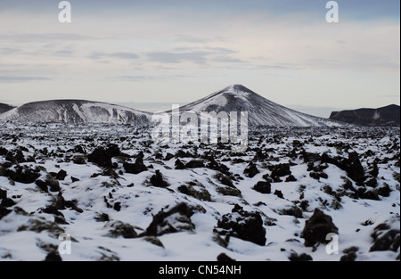 Island, Sudurnes Region, Grindavik, die blaue Lagune, Blick auf felsigen Lavafeld mit schneebedeckten Hügeln Stockfoto