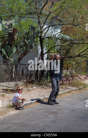 Ein Mann steht an der Seite einer Straße und eine Balsa Holz Spielzeug Segelflugzeug Flugzeug mit einem kleinen Jungen neben ihm hält. Stockfoto