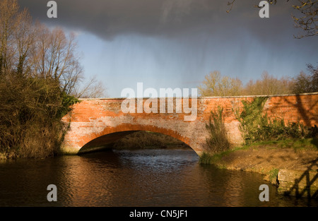 Rote Ziegelbrücke über Fluss Deben mit Regen am Ufford, Suffolk, England Stockfoto