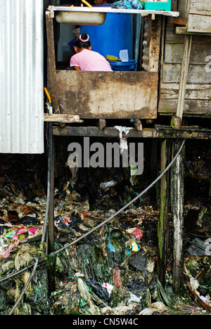 Malaysia, Borneo, Sabah State, Semporna, Frau waschen in Stelzenhaus mit Müll unter Stockfoto