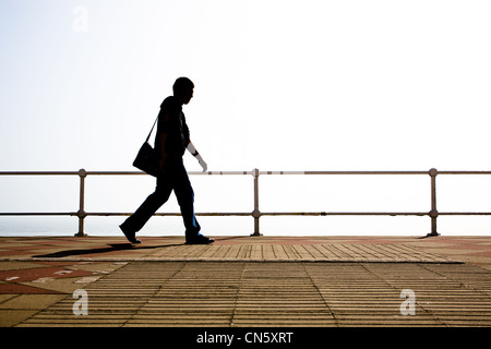 Silhouette der Mann zu Fuß entlang der Strandpromenade. St Leonards On Sea, Hastings, East Sussex, England, UK Stockfoto