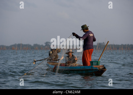 Fischerinnen und Fischer in der Dämmerung sammeln ihren Fang von Netzen und Käfige fiel auf das Bett des Songkhla-See. Stockfoto