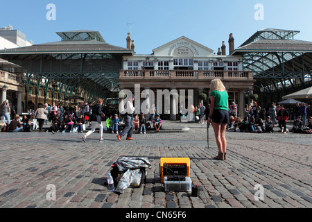 Entertainer führt mit zwei weiblichen Touristen in Londons Covent Garden Square Stockfoto