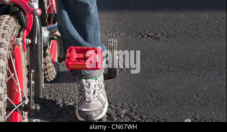 Ein Kind lernt, mit dem Fahrrad mit Stützrädern fahren, in der Nähe Ernte von Pedal und Fuß mit Asphalt Textfreiraum Stockfoto