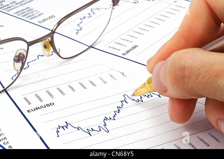 Hand mit Stift auf einen Finanzbericht Stockfoto