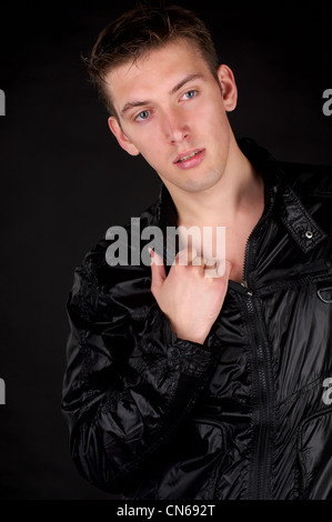 Gut aussehend Mann in schwarzer Jacke über schwarzen Hintergrund. Stockfoto