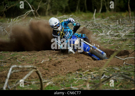 Racer Motocrossfahrer Ecke werfen viel Schlafplatz und Schmutz in der Luft hinter dem Motorrad herumfahren Stockfoto