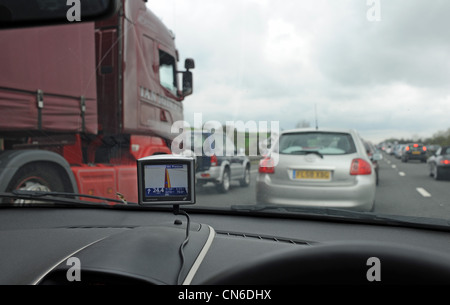 TomTom Navigation Satelliteneinheit am Armaturenbrett eines Autos stecken im ruhenden Verkehr auf der Autobahn M6 UK Stockfoto