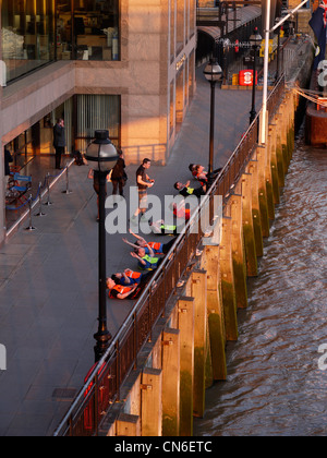 Personal Trainer leitet eine Bootcamp-Gruppe, die Sit-UPS an der Themse im Zentrum von London macht Stockfoto