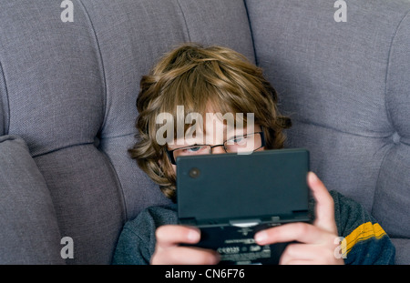 Ein Junge spielt auf einem Handheld Nintendo DSi-Spiele-Konsole Stockfoto