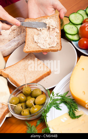 Detail der Küchentisch mit Essen und weibliche Hände machen Thunfisch Sandwich. Stockfoto